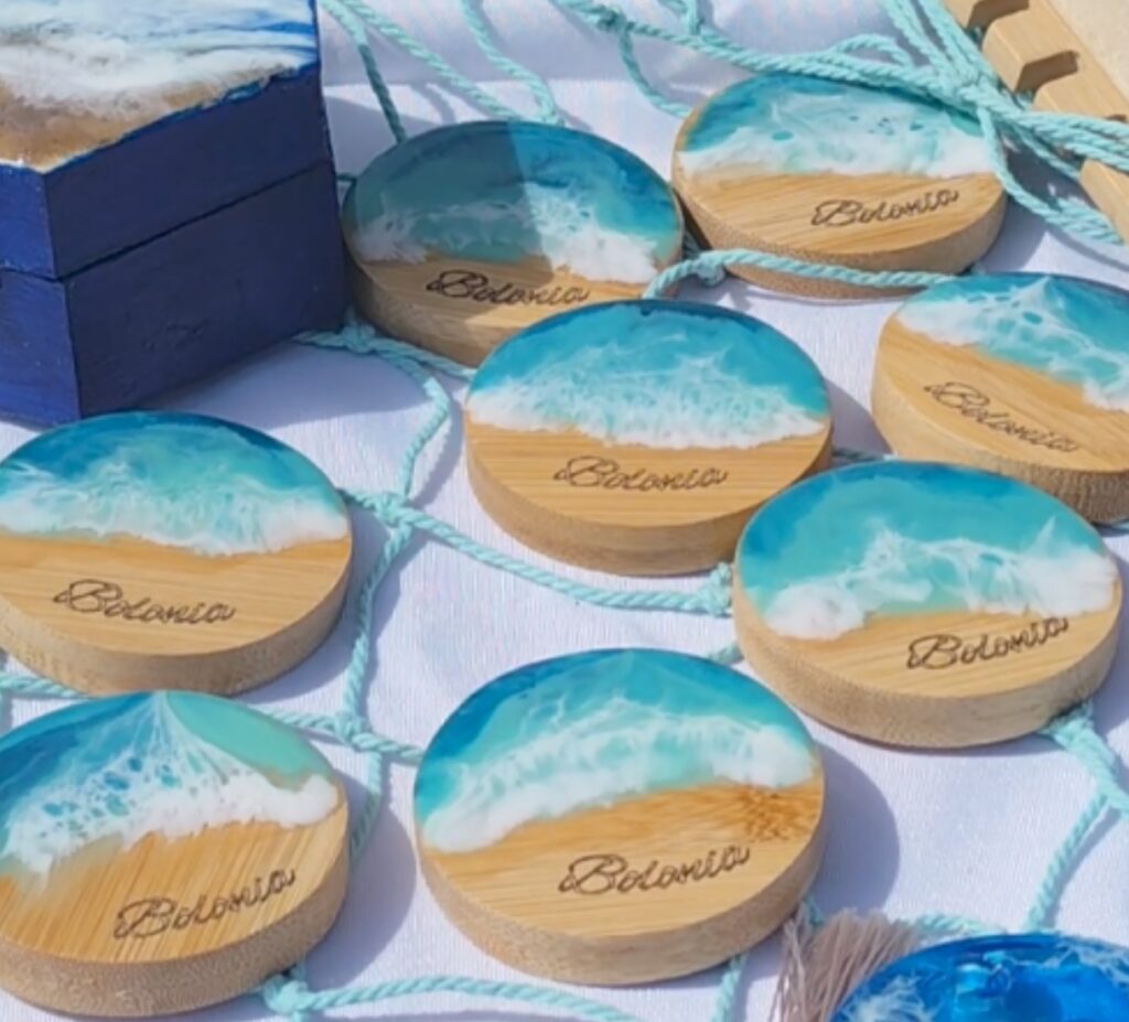 Abrebotellas de bambú con resina azul y efecto mar, con imán para nevera. Con bambú que evoca la arena y resina que refleja el mar, Orilla Azul es un detalle funcional y lleno de encanto costero.

